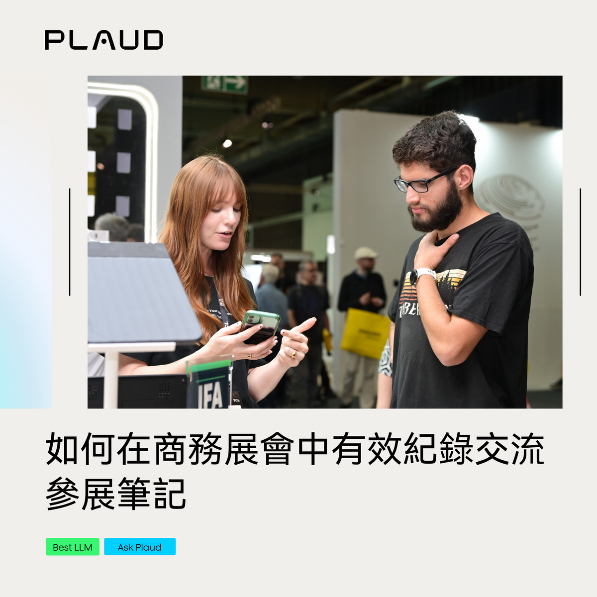 兩人在商務展會上交流，一人展示手機，另一人專注聆聽。